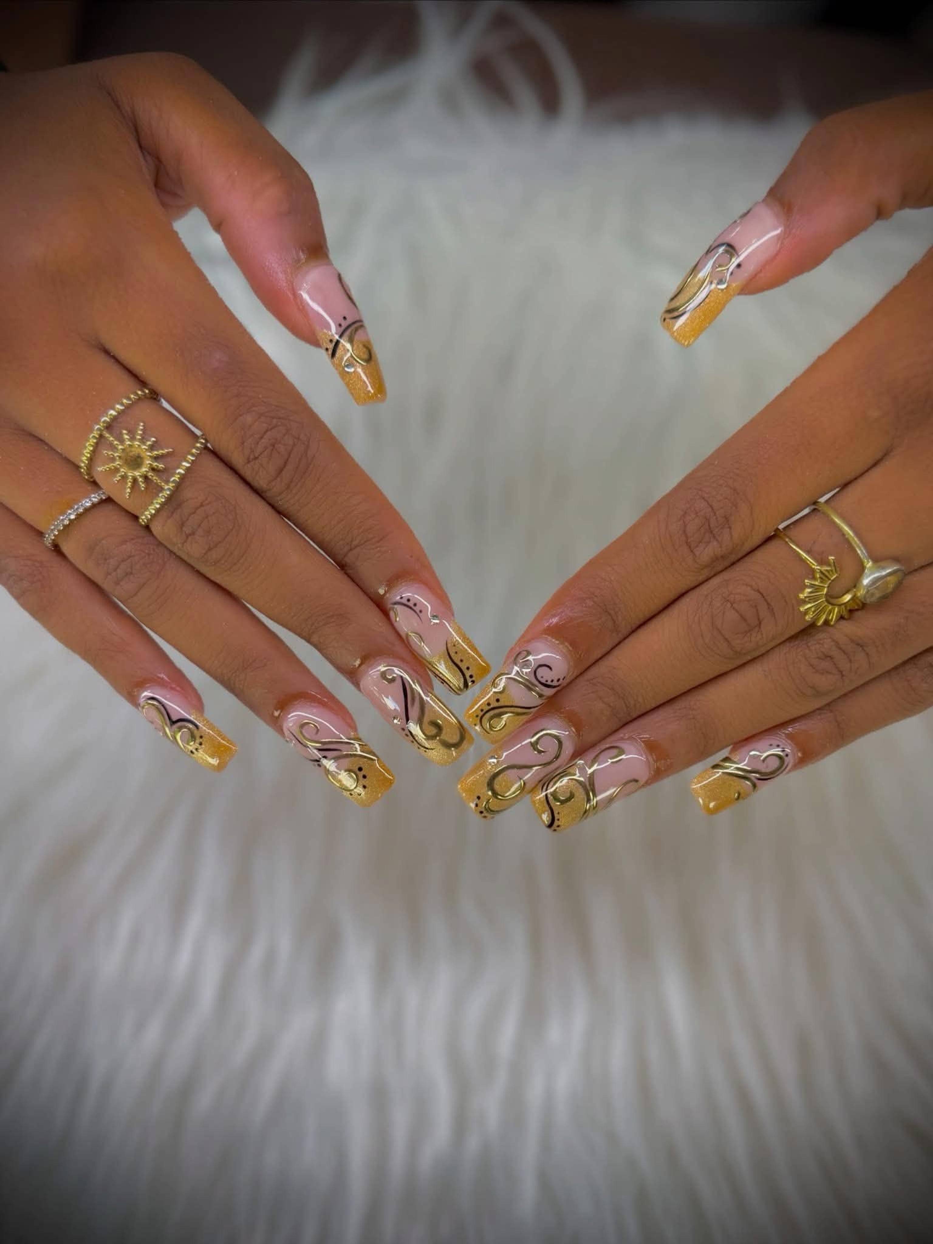 Long coffin nails with gold glitter tips and black and gold swirl line work